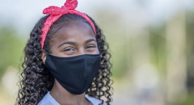 Smiling youth wearing mask outdoors