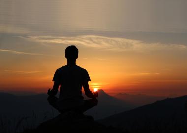 Man meditating at sunrise