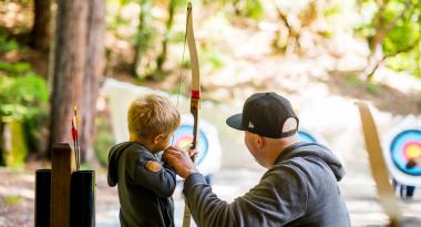 father teaching son archery