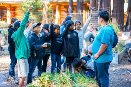 teenager asking a question to younger campers