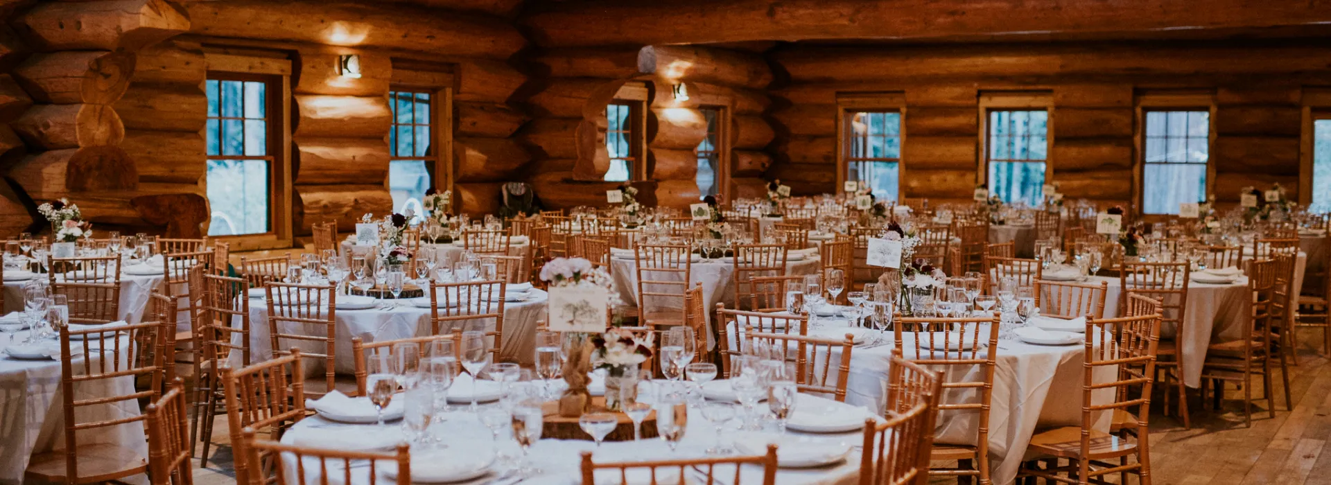 Log cabin style dining hall with tables set up for a wedding