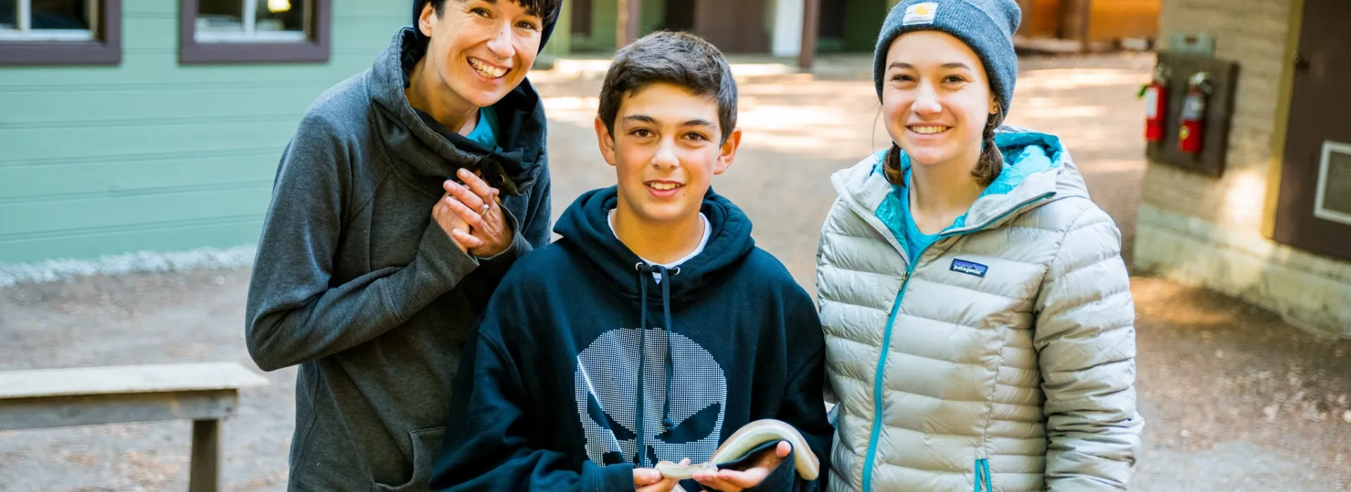 student smiling holding snake with teachers
