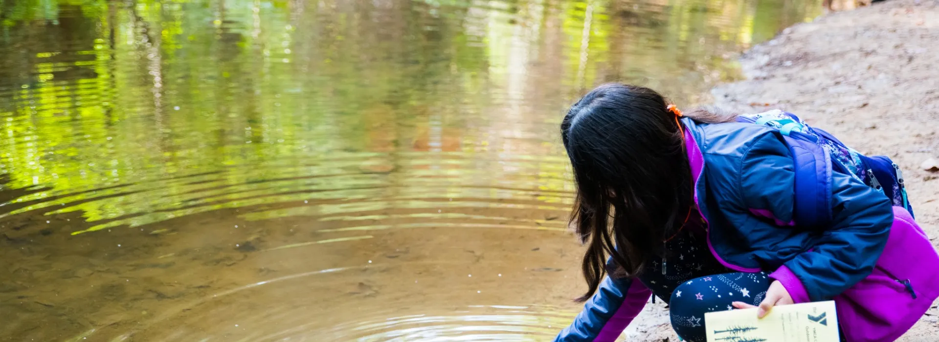 girl scooping water out of a river